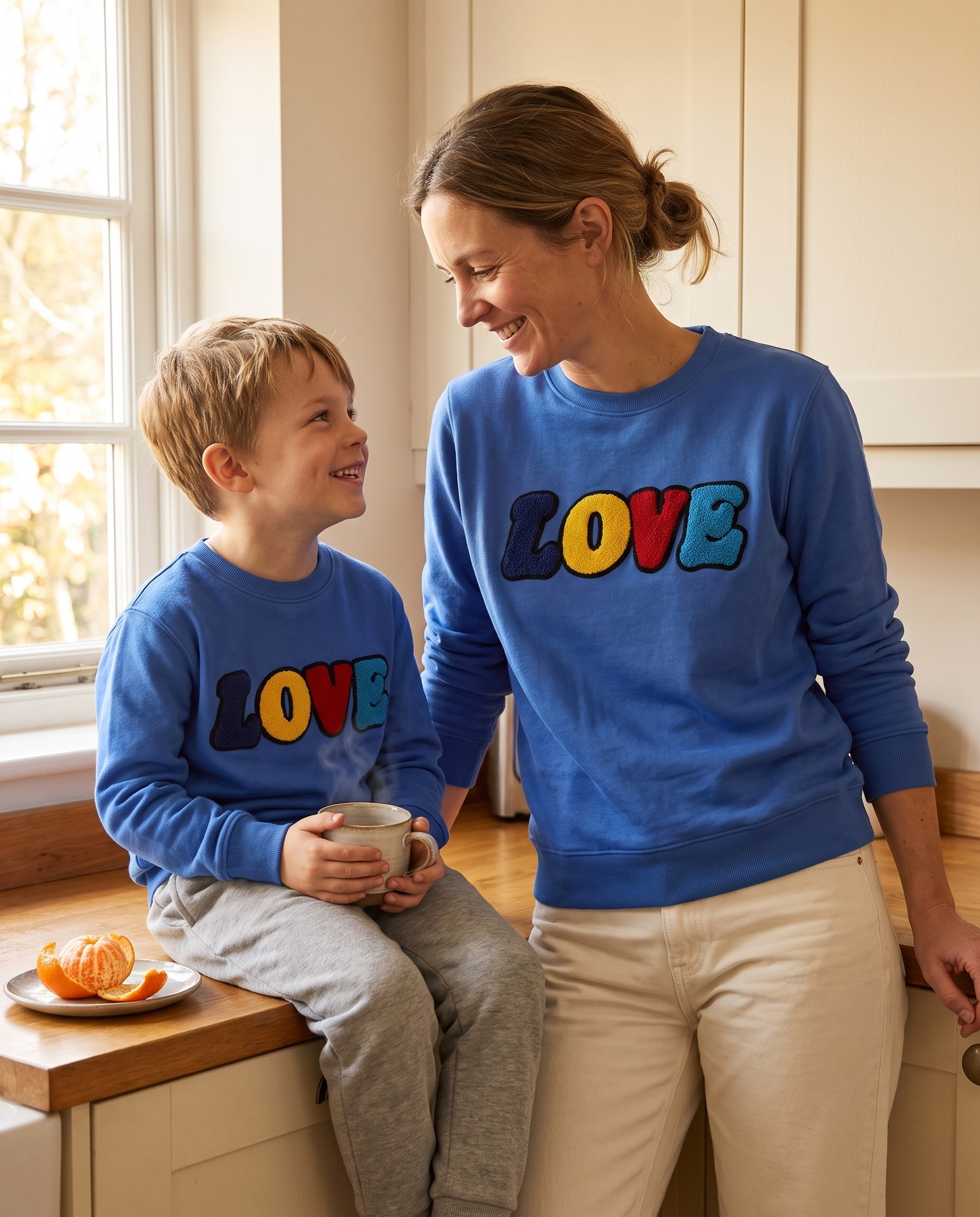 Mutter und Sohn im LOVE Sweatshirt in heller Küche mit Kakao